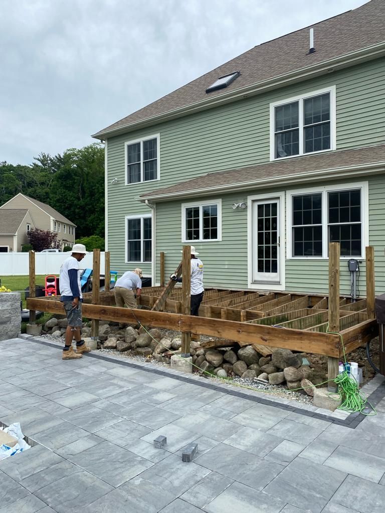 a group of people are working on a wooden deck in front of a house