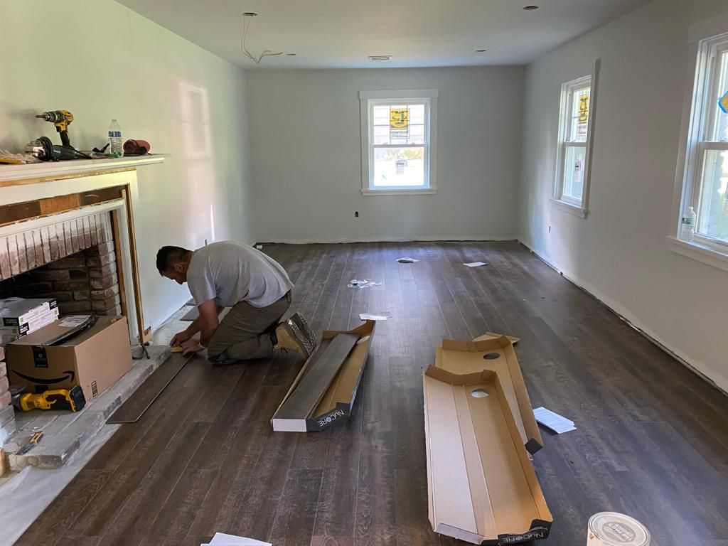 a man is installing hardwood flooring in a living room .