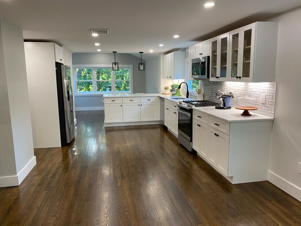 a kitchen with white cabinets, stainless steel appliances, and hardwood floors