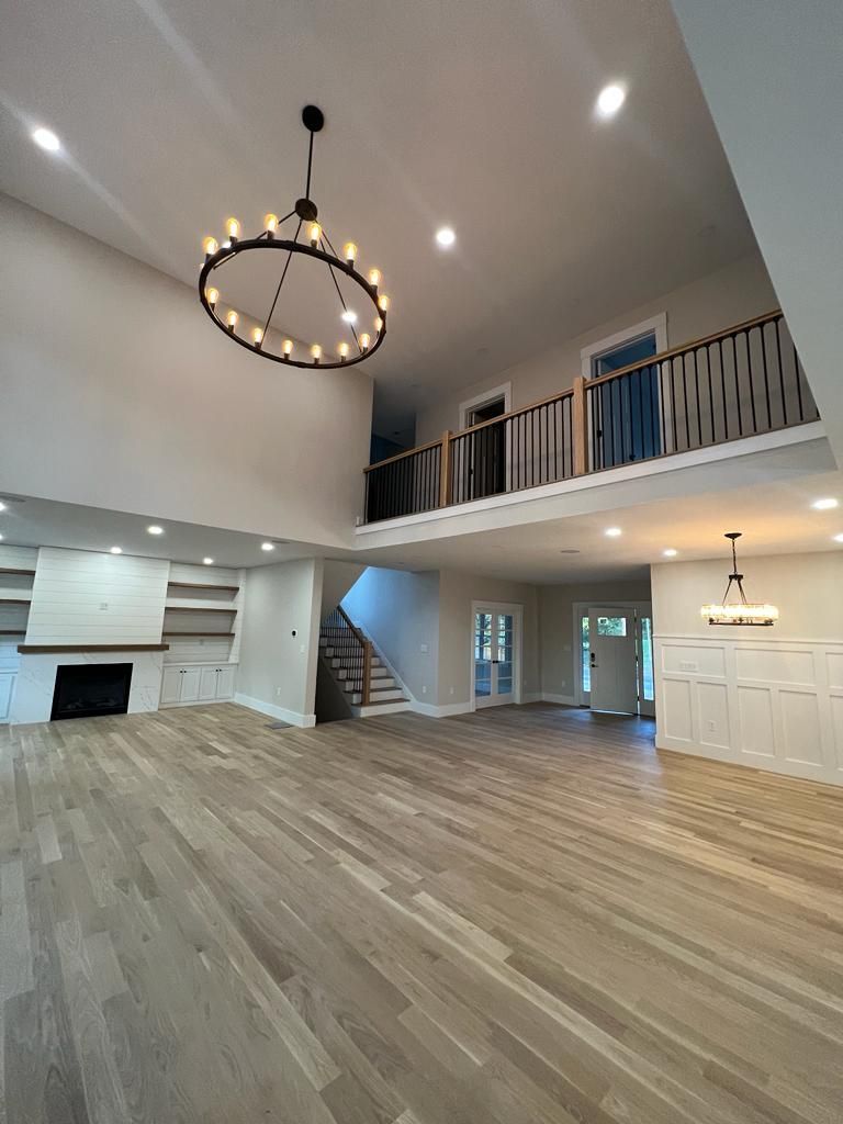 a large empty room with hardwood floors and a chandelier hanging from the ceiling