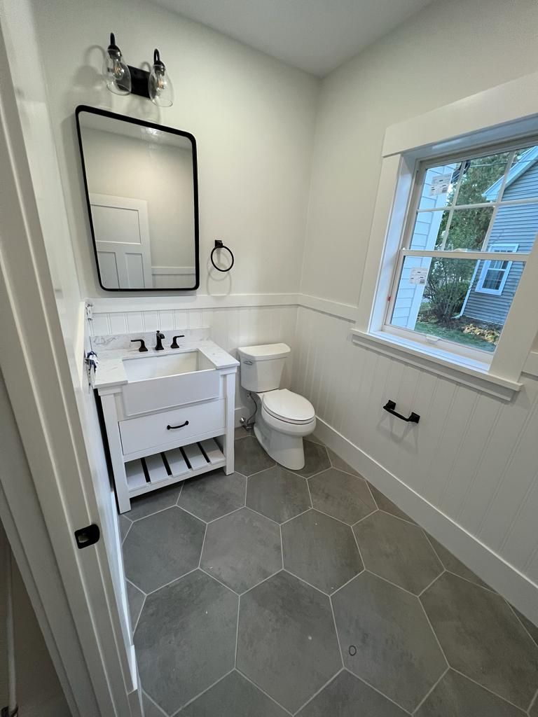 a bathroom with a sink, toilet, mirror and window
