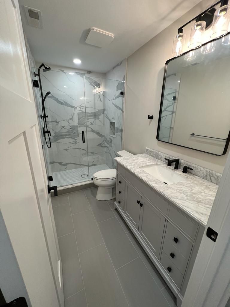 a bathroom with a toilet, sink, mirror and shower