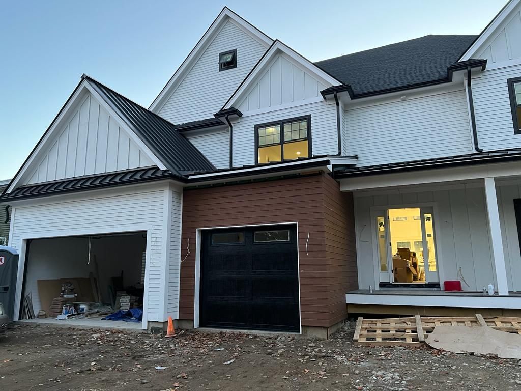a large white house with a black garage door is being built