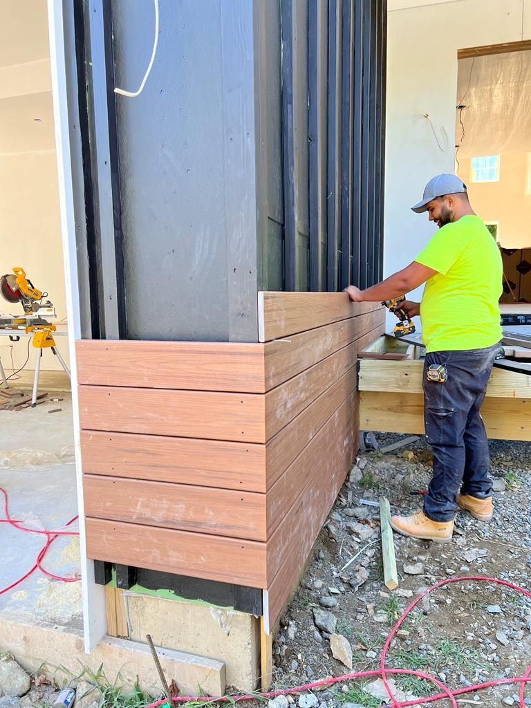 a man in a yellow shirt is standing next to a wooden wall