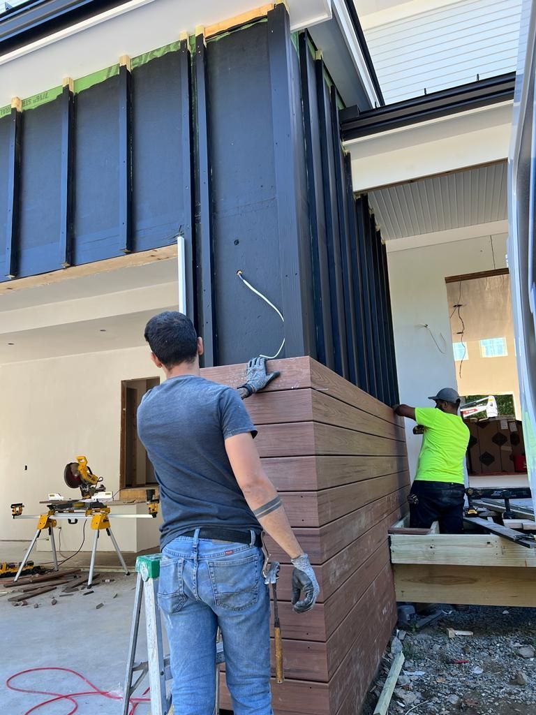 a man is standing in front of a building holding a piece of wood