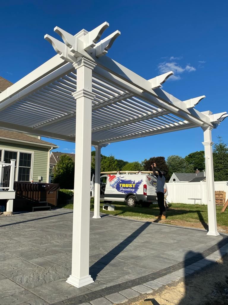 a white pergola is sitting on top of a patio next to a house