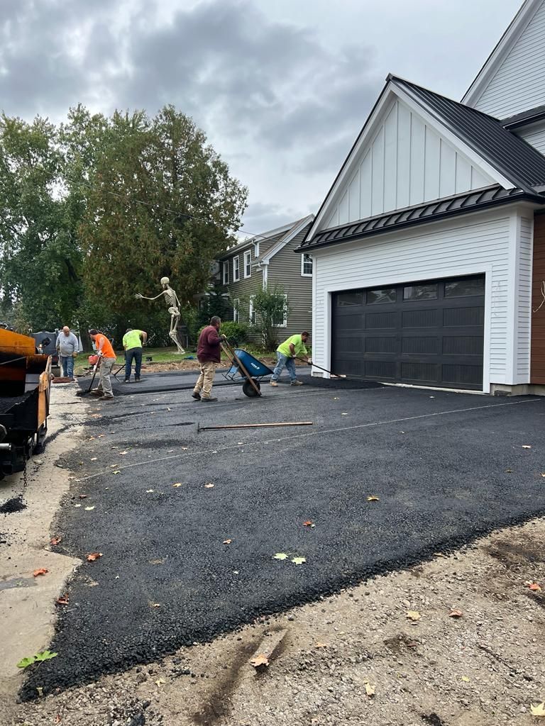 a group of people are working on a driveway in front of a house