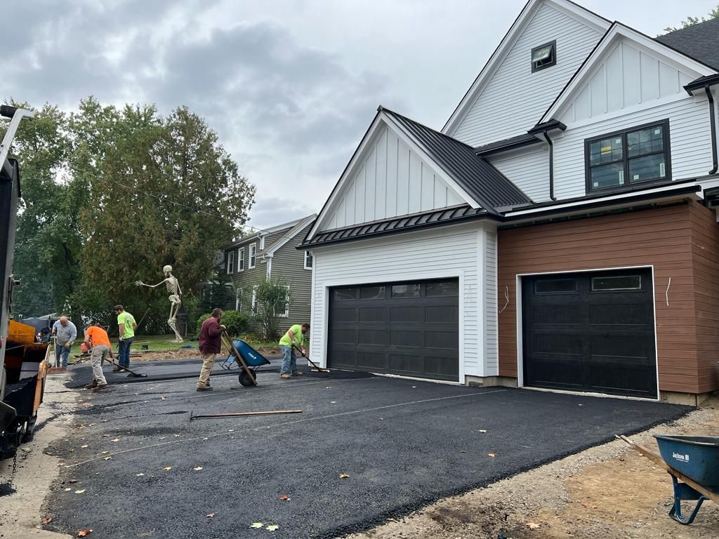 a group of people are working on a driveway in front of a house