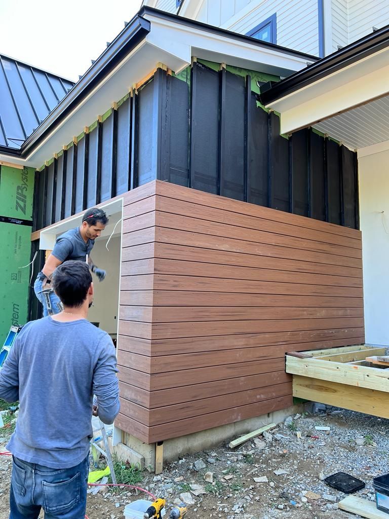 two men are working on the side of a house