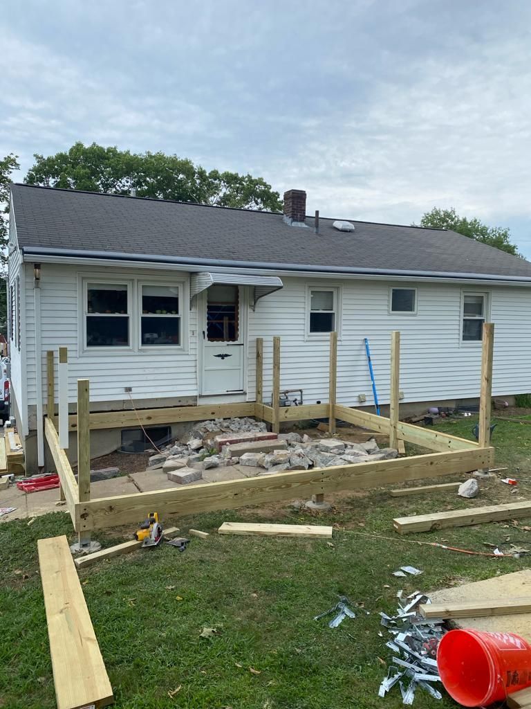 a white house with a wooden deck being built in front of it