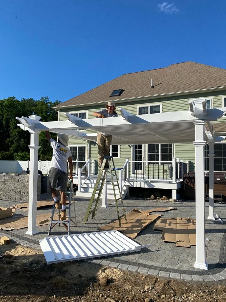 a man is standing on a ladder working on a pergola in front of a house