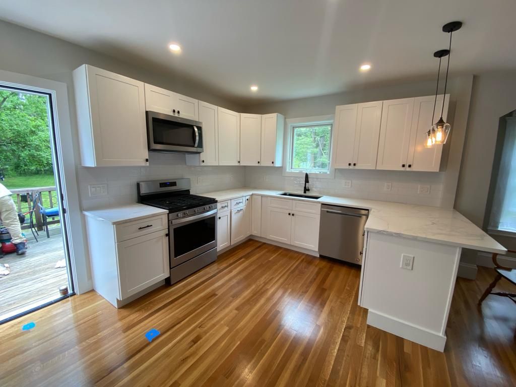 a kitchen with white cabinets, stainless steel appliances, and hardwood floors
