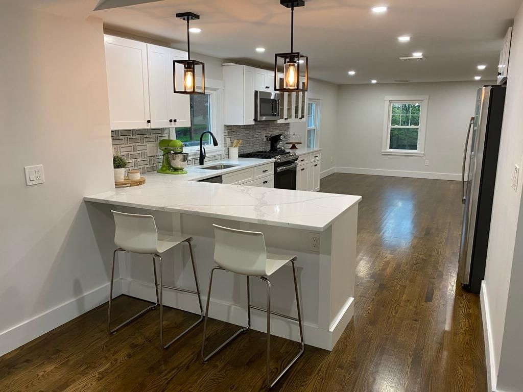 a kitchen with white cabinets, stainless steel appliances, hardwood floors, and a large island