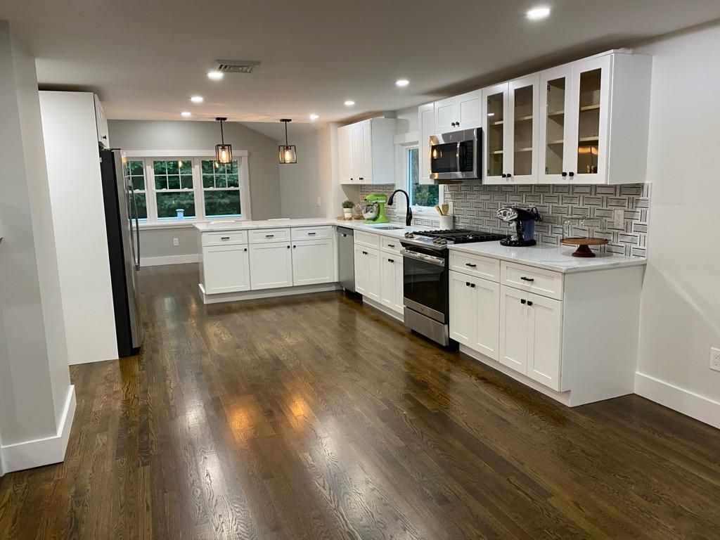 a kitchen with white cabinets, stainless steel appliances, and hardwood floors