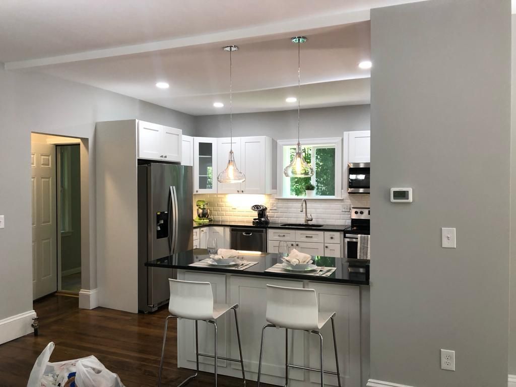 a kitchen with white cabinets, stainless steel appliances, a refrigerator and a bar