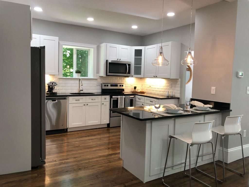 a kitchen with white cabinets, stainless steel appliances, and a large island