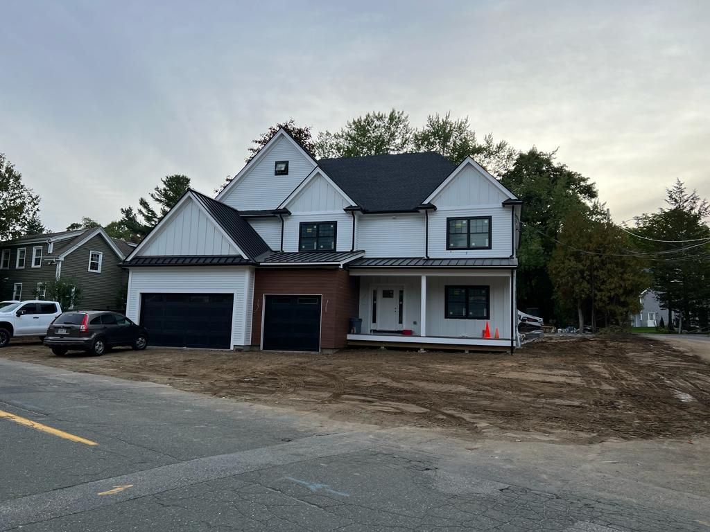 a large white house with a black roof is being built