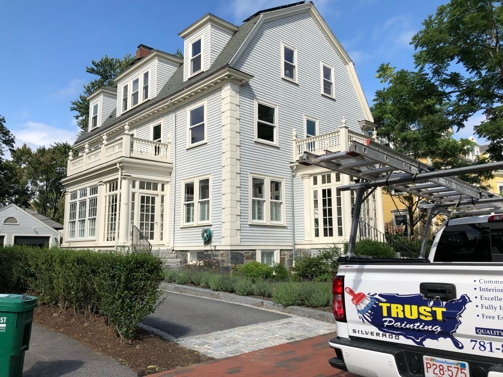 a white truck with the word trust on the back is parked in front of a large white house