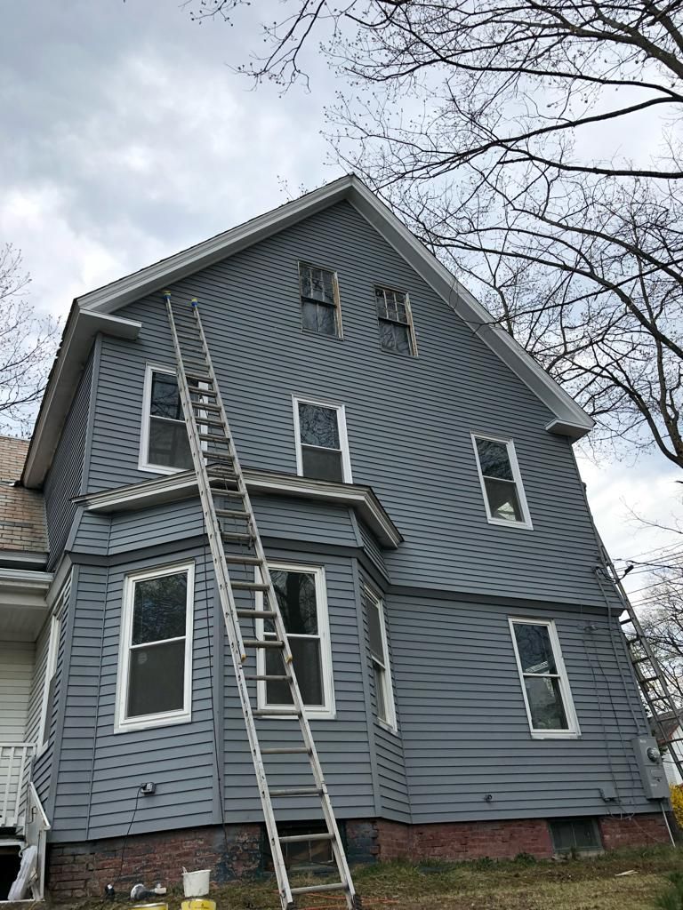 a large gray house with a ladder on the side of it