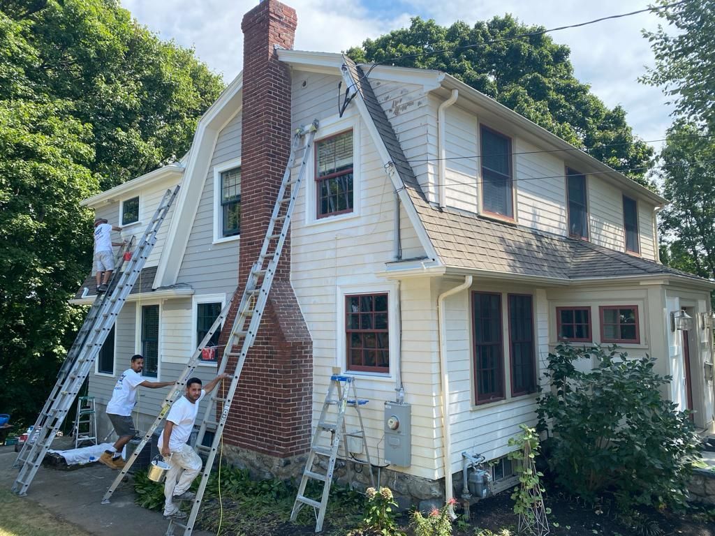 a group of people are painting a house with ladders