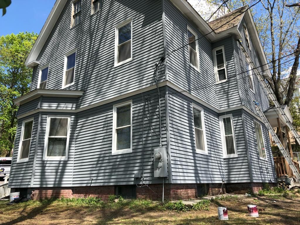 a large gray house with a lot of windows is being painted