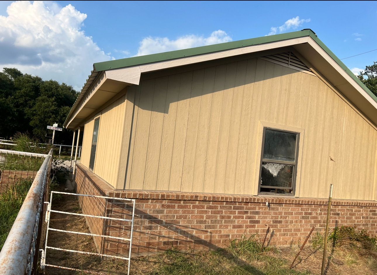 A house with a green roof is sitting on top of a hill.