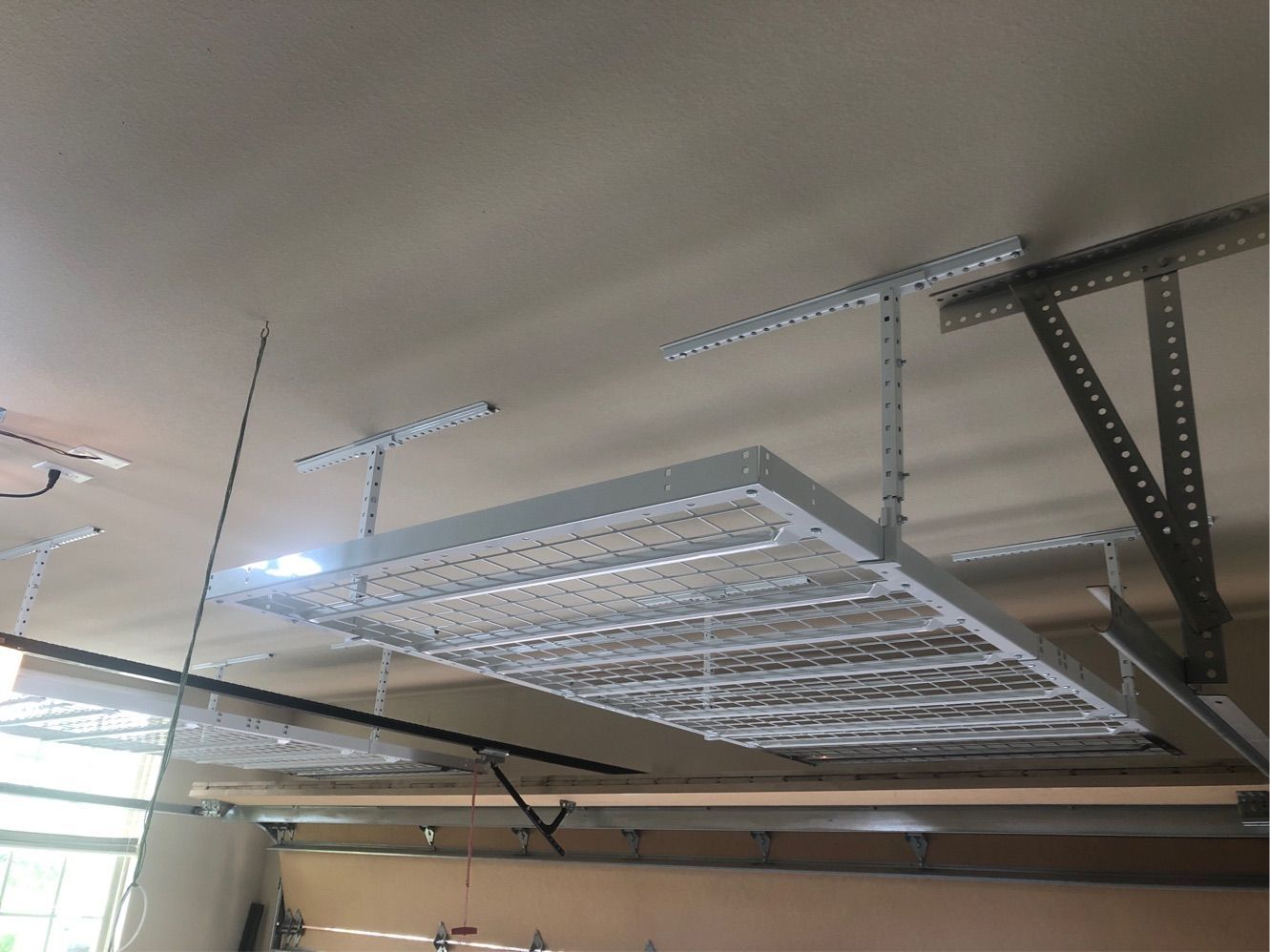 A metal rack is hanging from the ceiling of a garage.