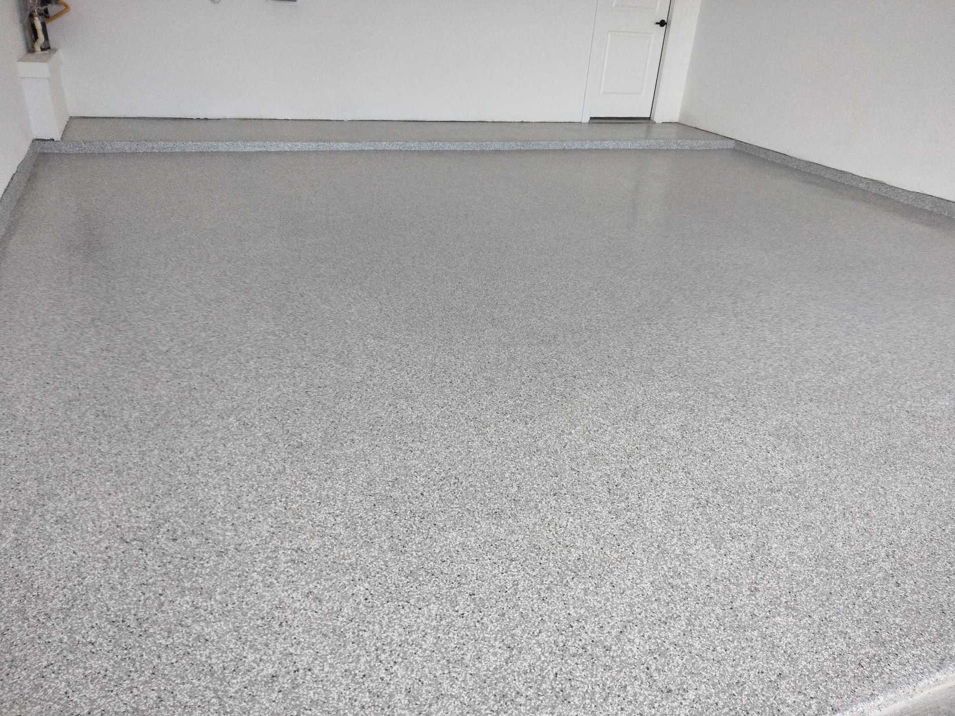 A garage with a gray concrete floor and white walls.