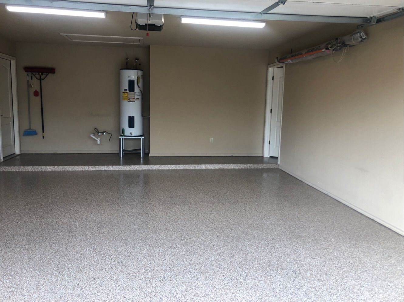 An empty garage with a water heater and a broom.