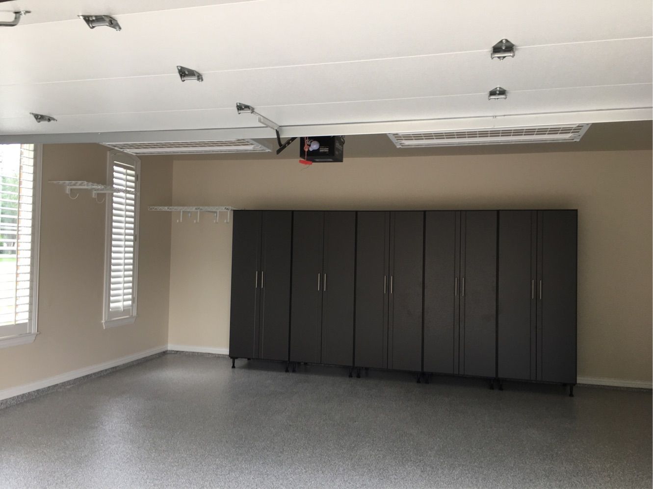 An empty garage with lots of cabinets and a garage door open.