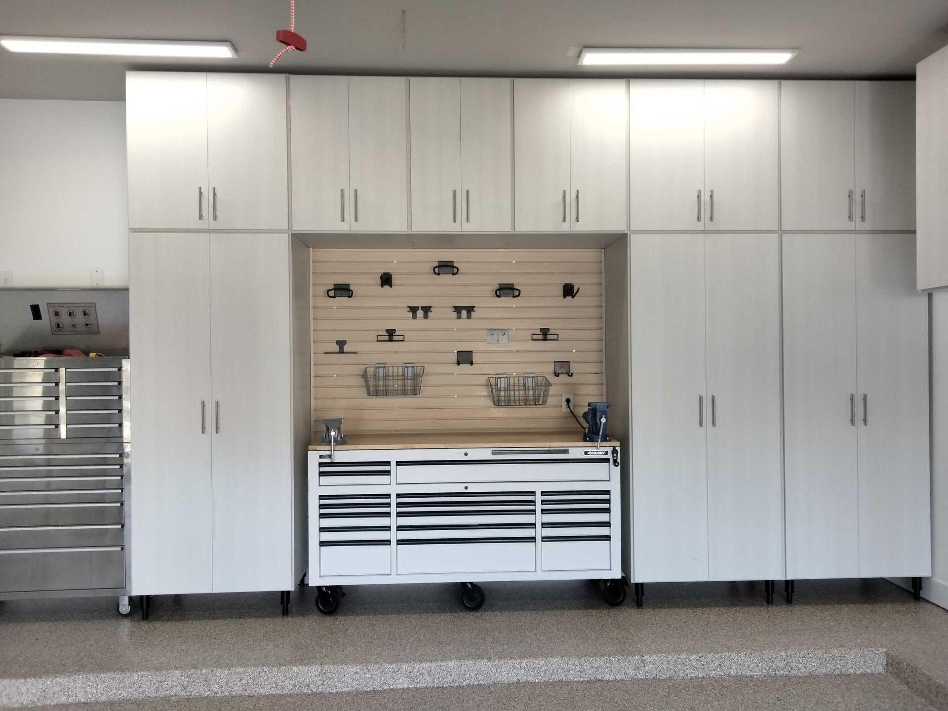 A garage with lots of white cabinets and a workbench