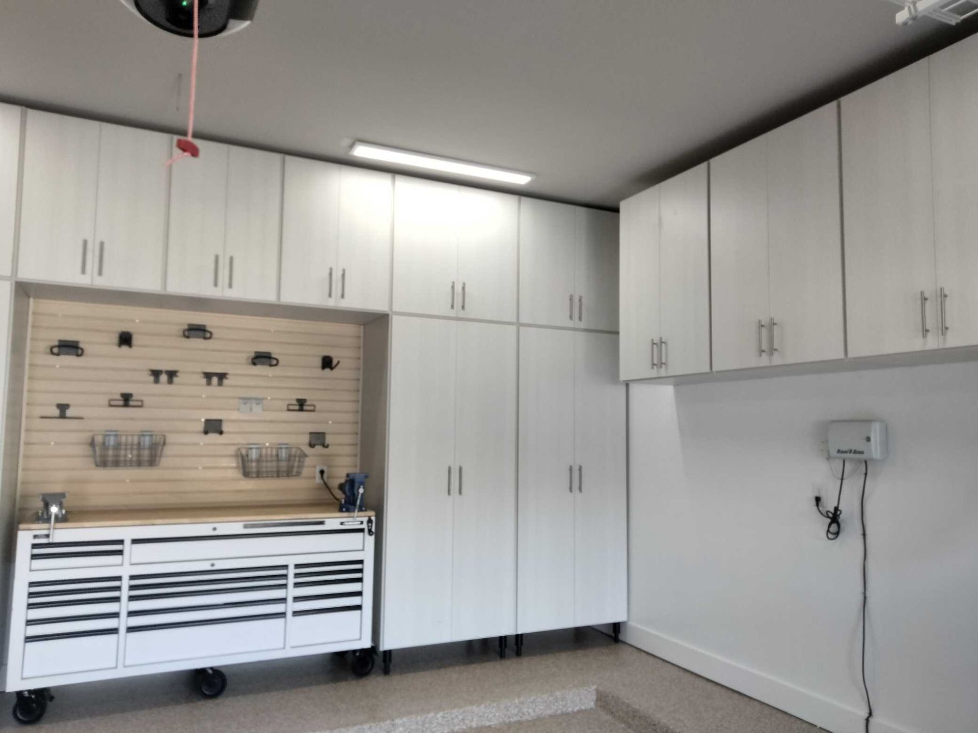 A garage with white cabinets and a workbench