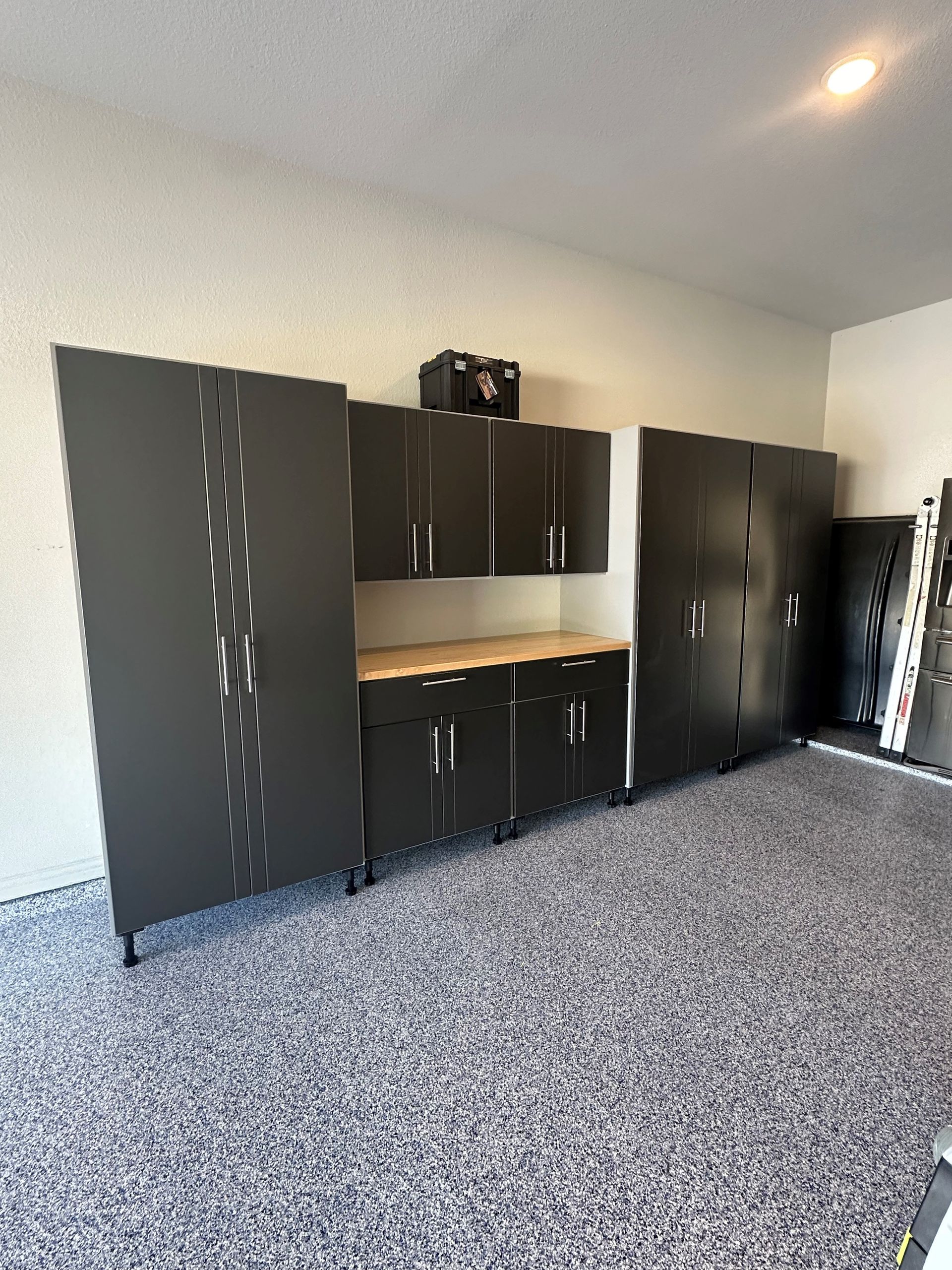 A garage with a lot of cabinets and a carpeted floor.
