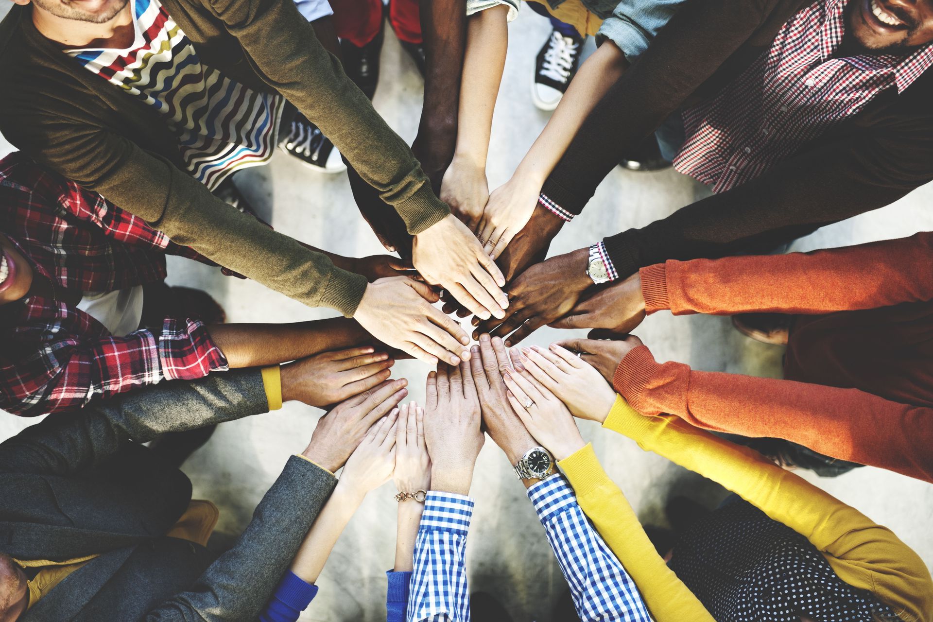 a group of people are putting their hands together in a circle .