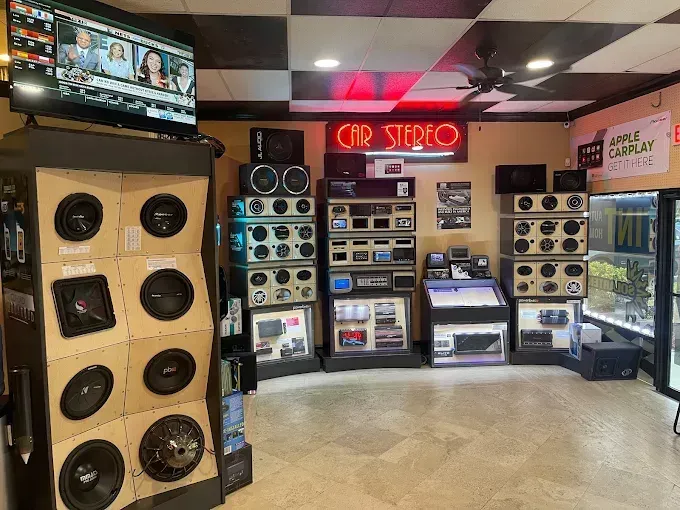 Audio store interior with stacked speakers, stereo equipment, and a red neon “SPL” sign