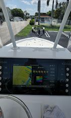 Boat dashboard view of a road ahead with palm trees and traffic lights through the windshield