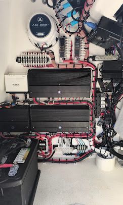 Wall-mounted home theater setup with two large flat-screen TVs, speakers, and a digital clock display