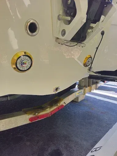 Close-up of a white vehicle’s lower side with a red tow hook and curbside road markings.