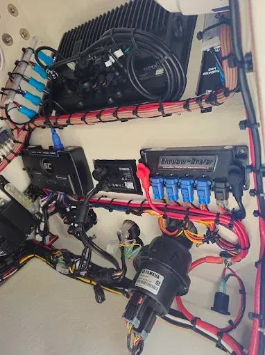 Electrical wiring panel with bundled red, black, and blue cables and mounted components inside a beige enclosure