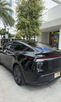 Black SUV parked outside a modern building with trees and glass windows