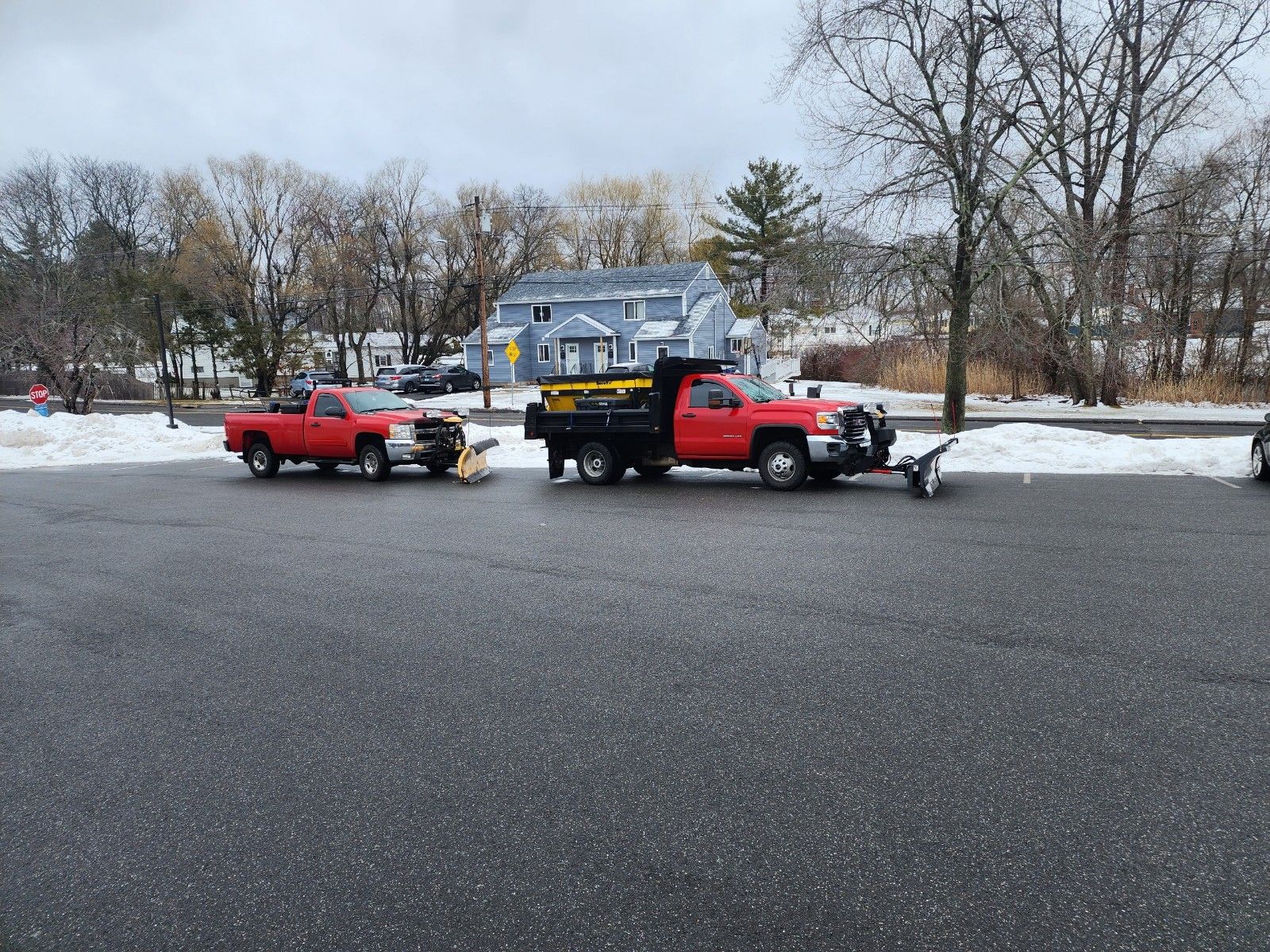 Two red snowplow trucks parked on a road, ready to clear snow.