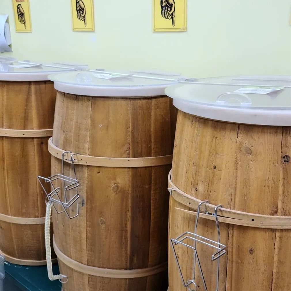 Wooden barrels with white lids and metal utensils in a store setting.
