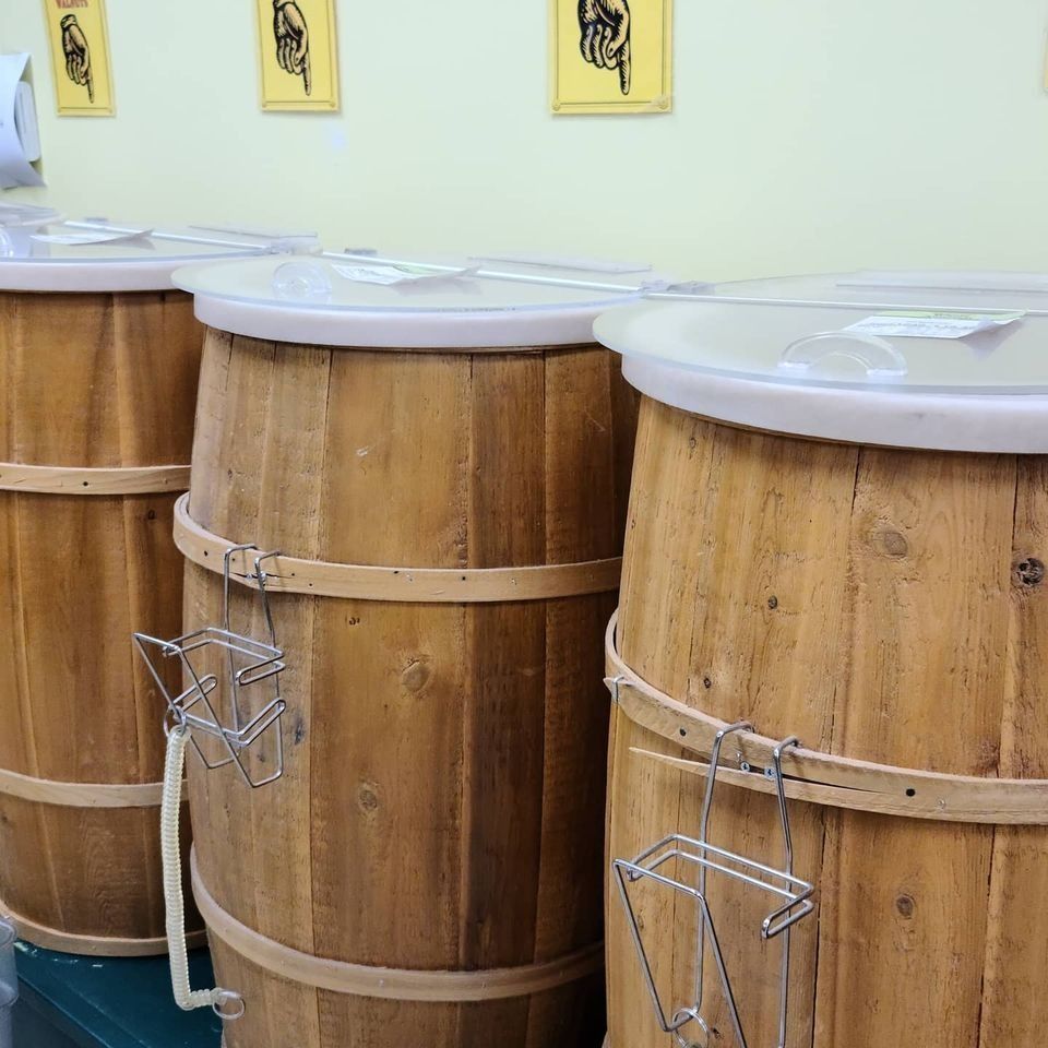 Wooden barrels with clear lids and utensil holders, indoors.