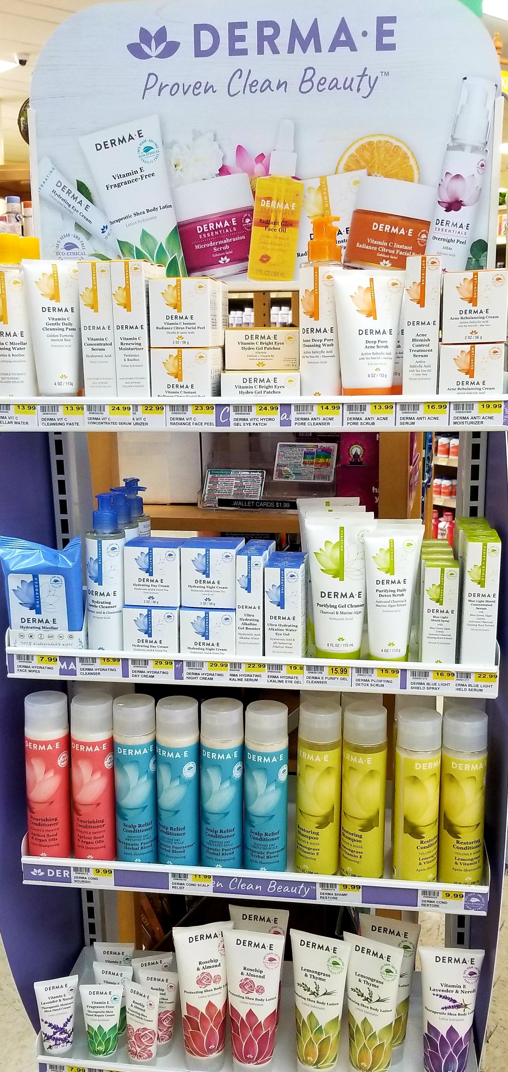 A display of Derma E beauty products on shelves in a store. Products are in various colors and packaging.