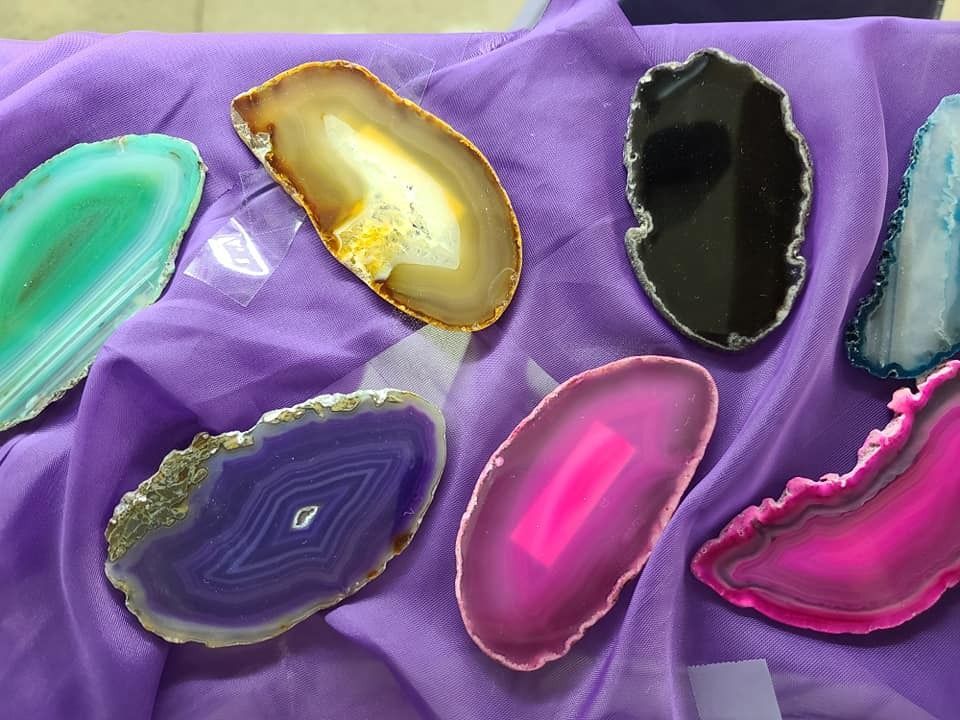 Colorful agate slices on a purple cloth; various colors including green, yellow, black, blue, purple, and pink.