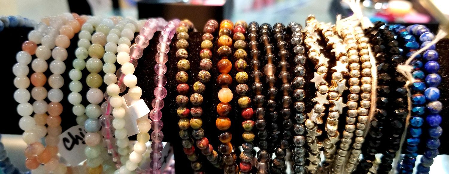 Close-up of various beaded bracelets in different colors, displayed for sale.