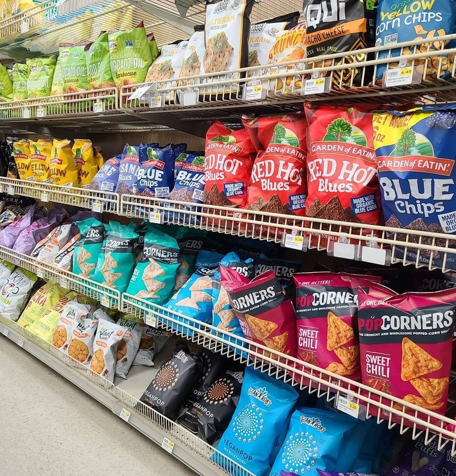 Shelves stocked with a variety of colorful chip bags in a grocery store aisle.