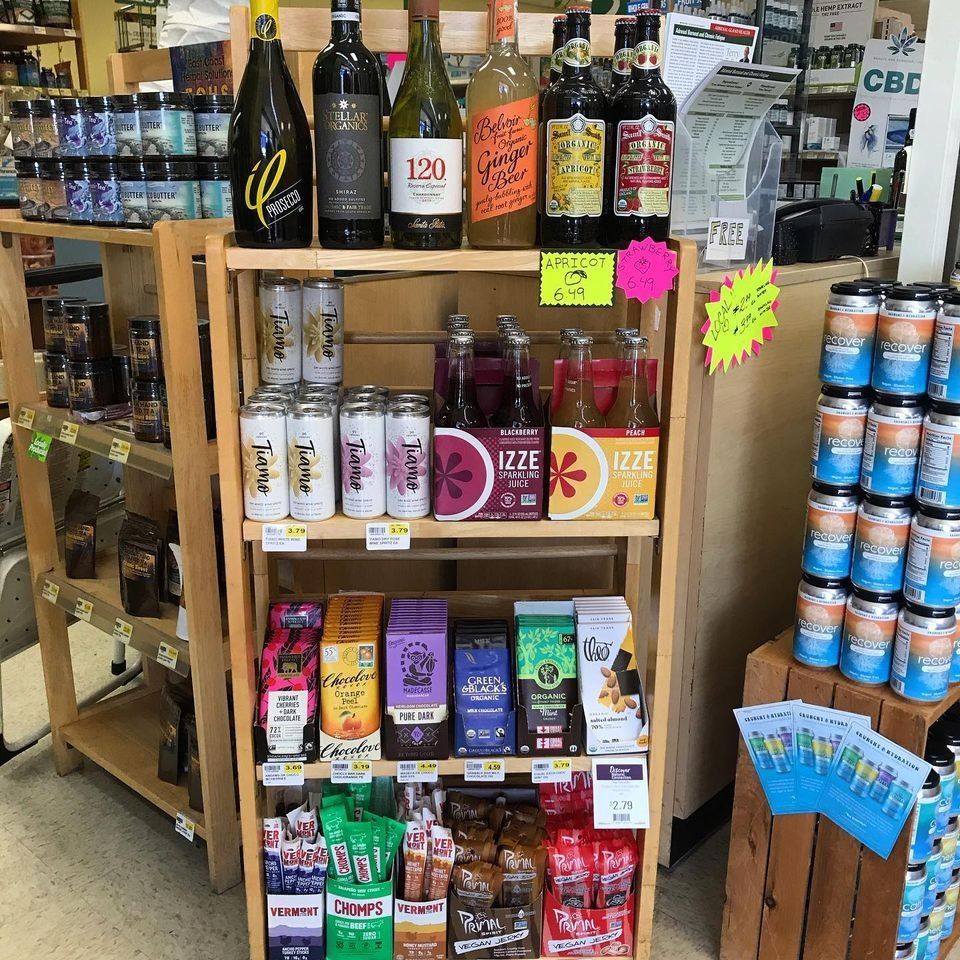 Wooden shelving unit in a store displaying beverages, snacks, and various items.