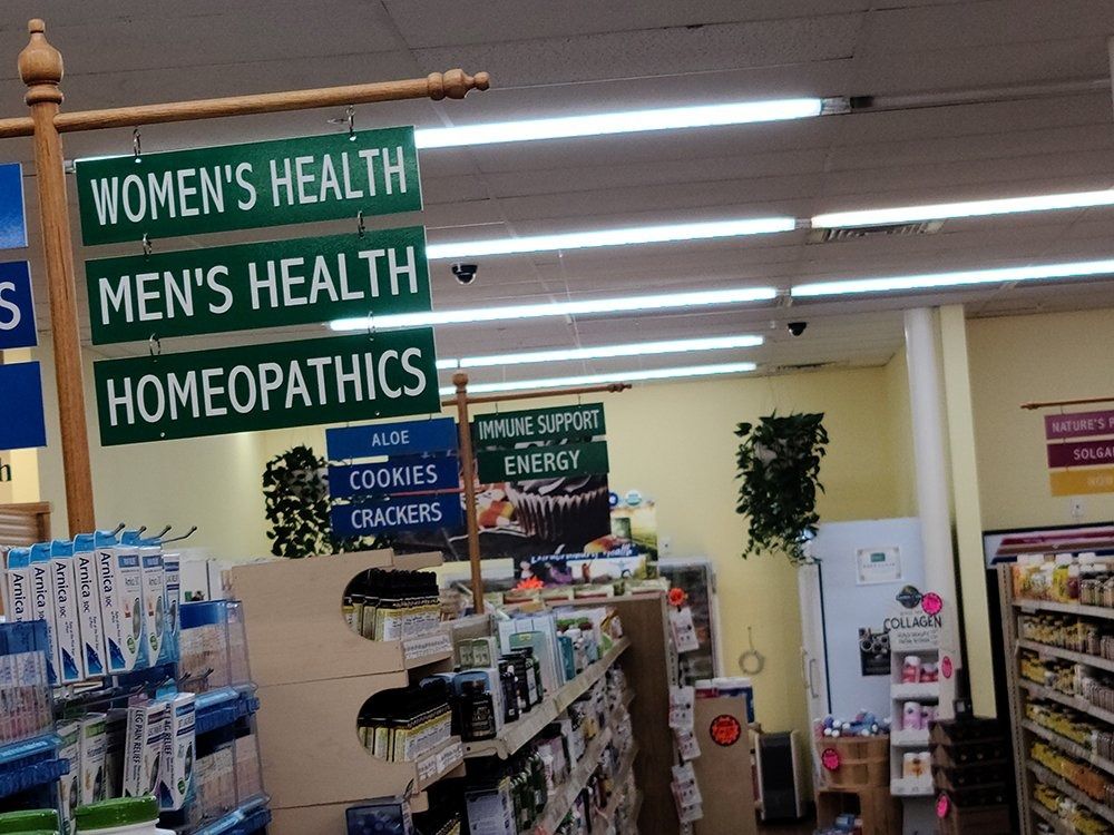 Signs for women's/men's health and homeopathics hang in a store aisle.