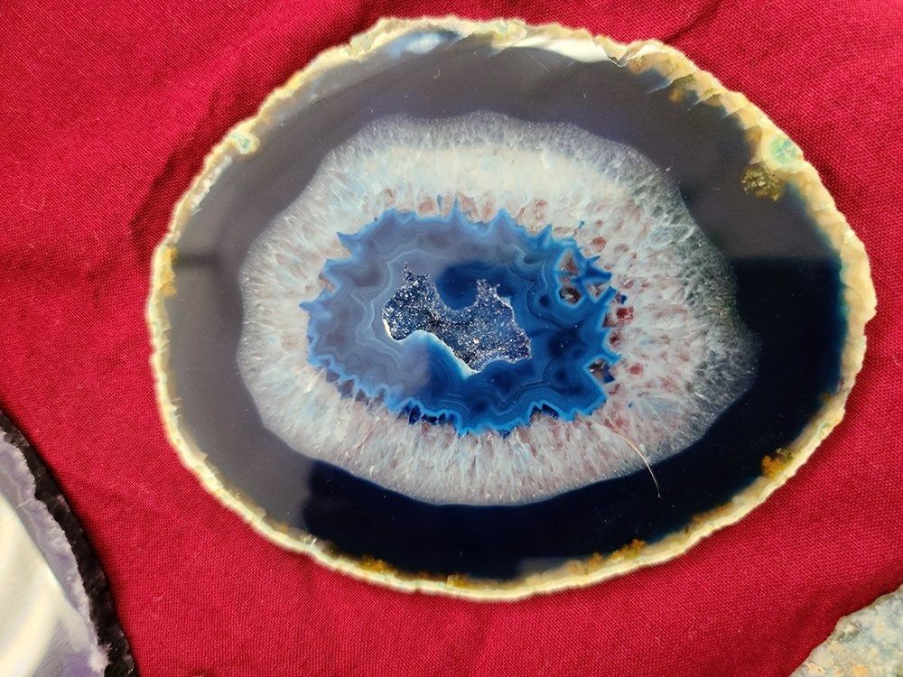 Blue and white agate slice with a dark blue center on a red background.